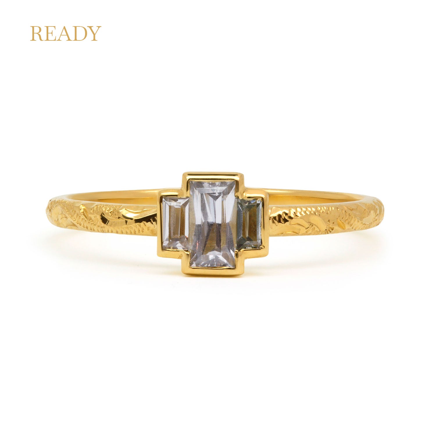 Fancy Hera ethical trilogy engagement ring in 18ct recycled yellow gold, hand-engraved and set with three grey baguette sapphires of fair-traded and traceable Sri Lankan provenance