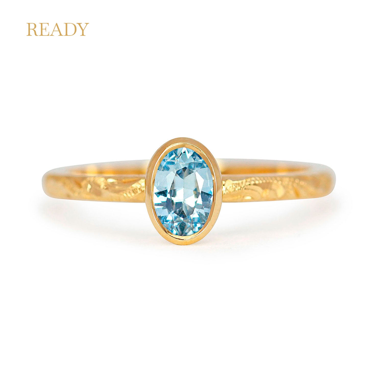 Fancy Hera ethical solitaire engagement ring in 18ct recycled yellow gold, hand-engraved and set with a ice blue oval-cut sapphire of fair-traded and traceable Sri Lankan provenance