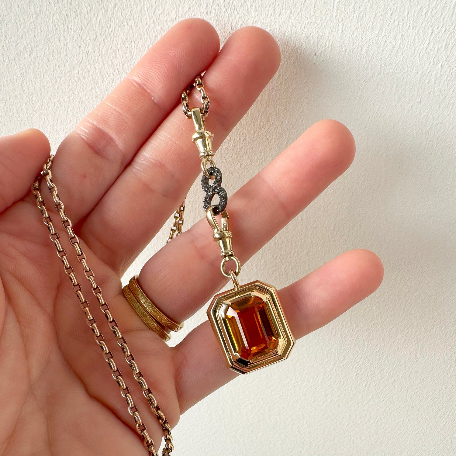 Reclaimed Vintage necklace with Brazilian quartz, recycled antique Victorian gold chain and connectors, and a black diamond figure-of-eight connector - lifestyle photo in hand 2