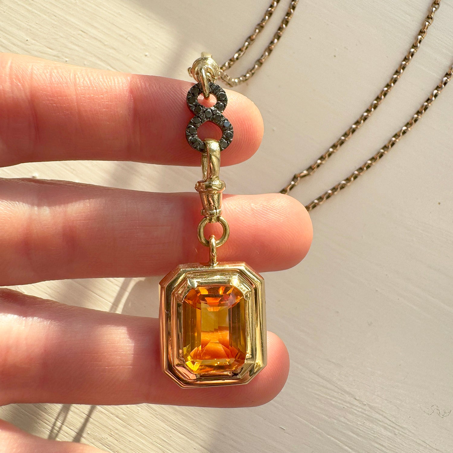Reclaimed Vintage necklace with Brazilian quartz, recycled antique Victorian gold chain and connectors, and a black diamond figure-of-eight connector - lifestyle photo in hand