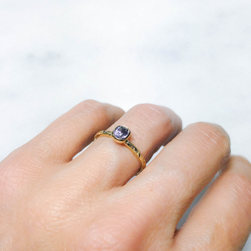 Fancy Hera ethical solitaire engagement ring in 18ct recycled yellow gold, hand-engraved and set with a purple cushion-cut spinel of fair-traded and traceable Sri Lankan provenance