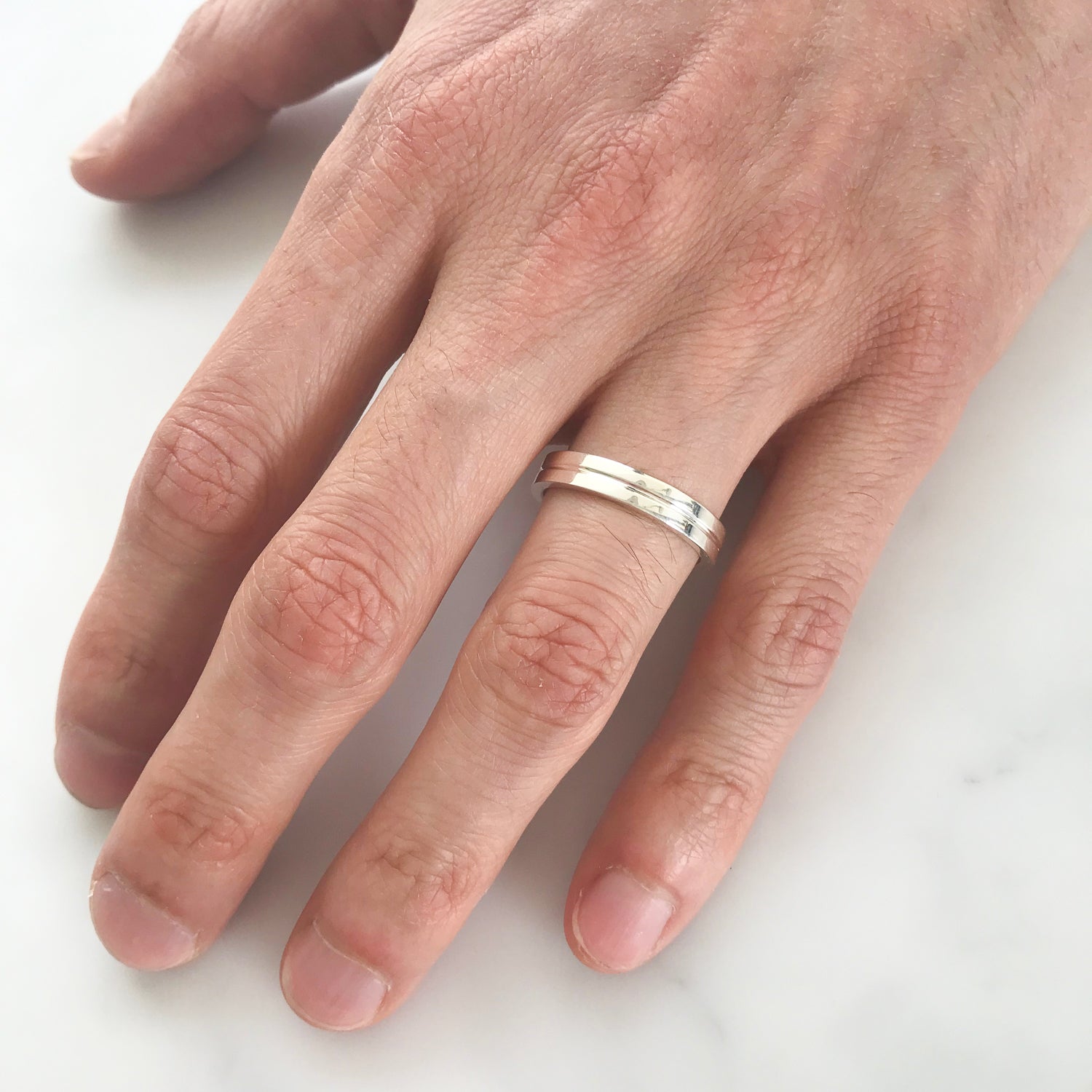 Flat men's wedding band cast in 100% recycled platinum, with a matte finish and a scored groove