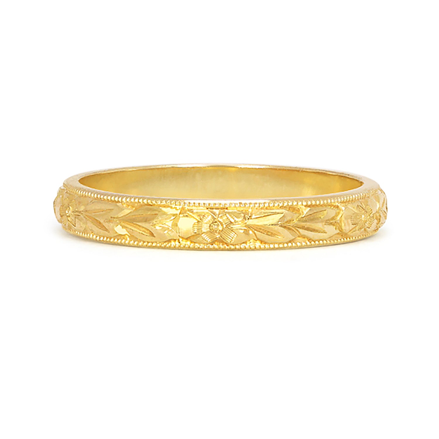 A D-shaped 2mm wedding band in 18ct recycled yellow gold, carefully hand-engraved with a repetitive orange blossom motif and a border of milgrain beading