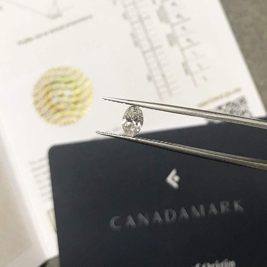 An oval-cut Canadamark diamond, ready to be secured into one of Lebrusan Studio's custom-made bespoke ethical solitaire engagement rings. Ethical jewelry UK