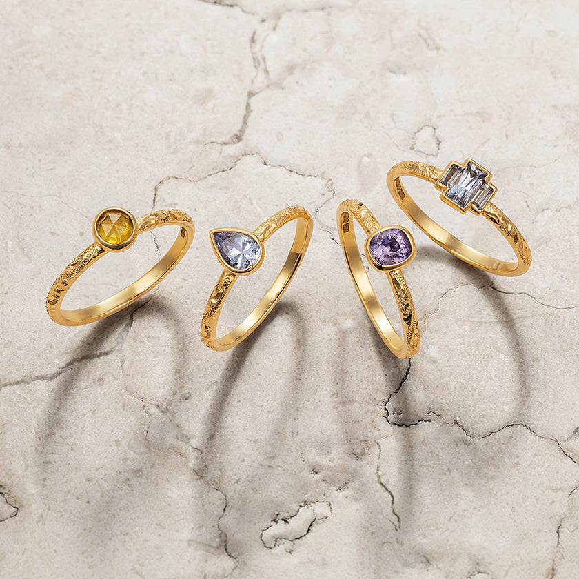 Lebrusan Studio's Candy Pop collection of ready-to-wear unique engagement rings. Delicate bands hand-engraved with a scroll pattern and ethical colorful sapphires are set in rub-over settings.