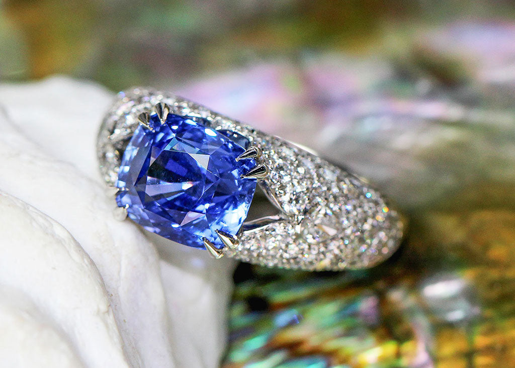 A large bespoke bombe cocktail ring, claw-set with a cushion-cut blue sapphire and grain-set with a plethora of conflict-free diamonds