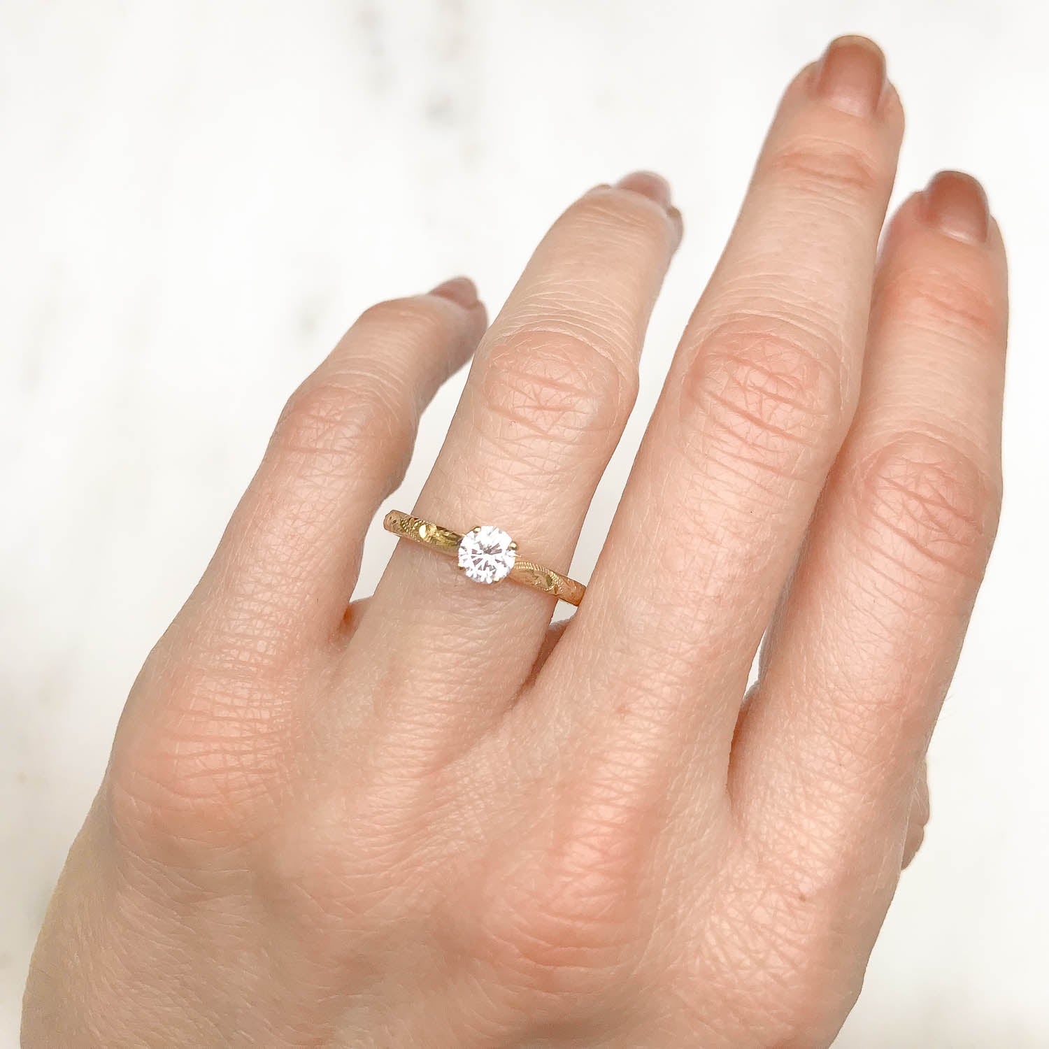 Solitaire engagement ring with a slim 18ct yellow gold band hand-engraved with intricate scrolls, and a 0.33ct round brilliant-cut diamond in a traditional four-claw setting, on hand 2