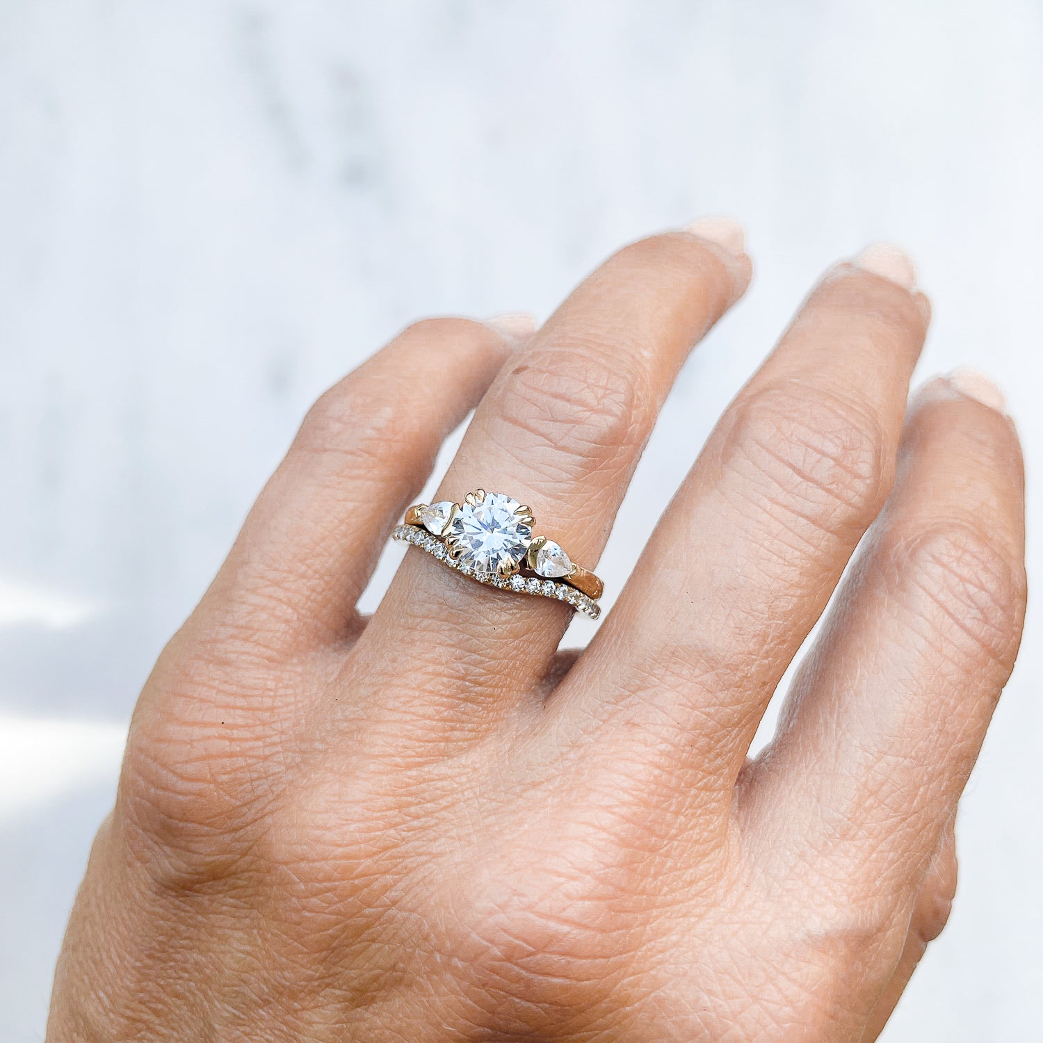 Lebrusan Studio Artisan Trilogy Engagement Ring, 1ct Ocean Diamond, 0.3ct pear-cut side Ocean Diamonds, 18ct Fairmined Ecological Gold, hand engraving, on hand, along with our shaped microset Accademia Ethical Diamond Wedding Ring