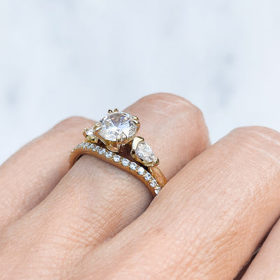 Lebrusan Studio Artisan Trilogy Engagement Ring, 1ct Ocean Diamond, 0.3ct pear-cut side Ocean Diamonds, 18ct Fairmined Ecological Gold, hand engraving, on hand, along with our shaped microset Accademia Ethical Diamond Wedding Ring 2