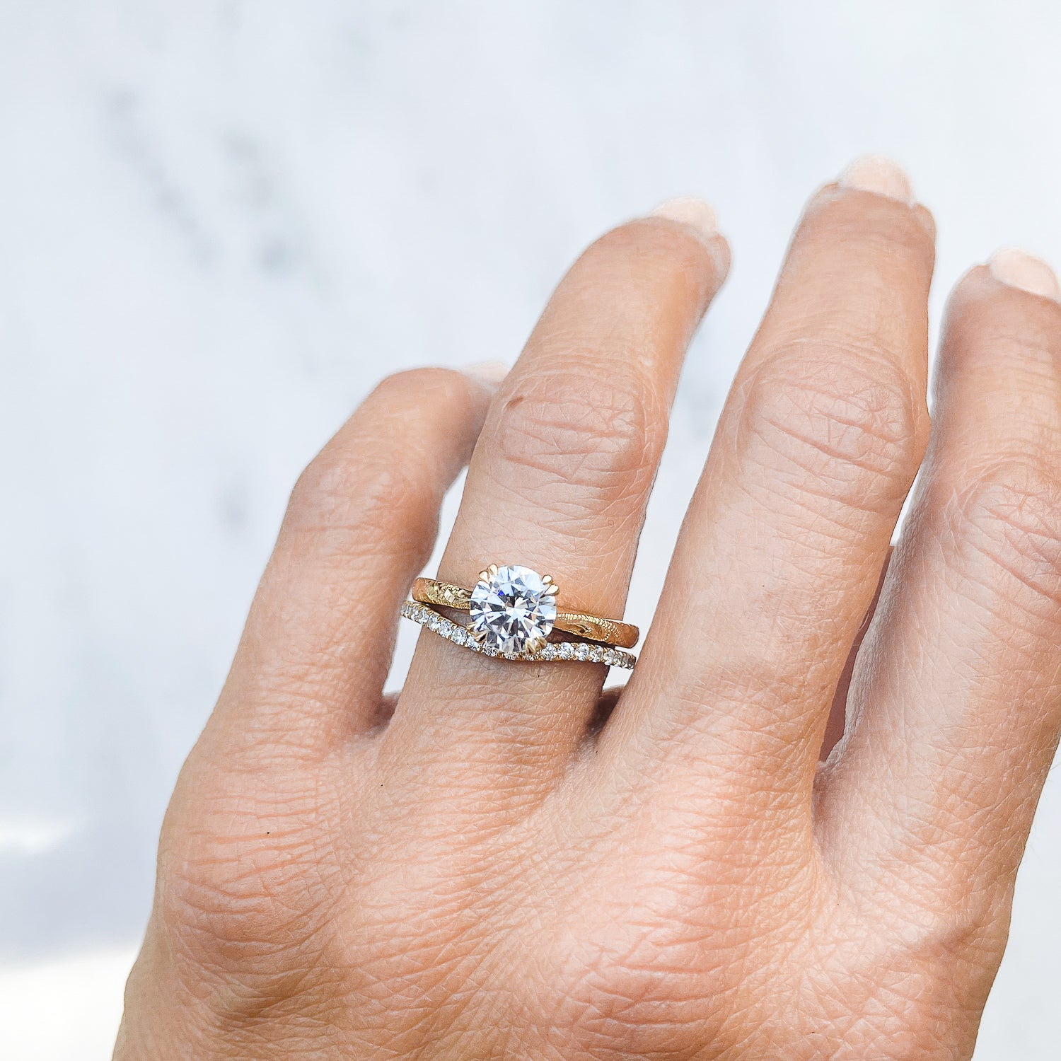 Lebrusan Studio Artisan Ethical Diamond Solitaire Engagement Ring, 1ct Ocean Diamond, 18ct Fairmined Ecological Gold, on the hand alongside the shaped microset Accademia Ethical Diamond Wedding Band