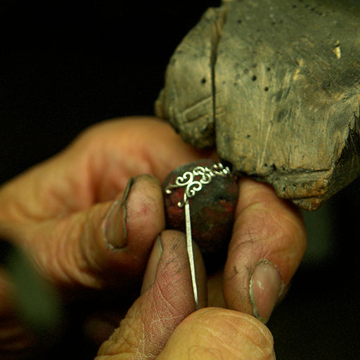 A goldsmith hand-crafting a bespoke engagement ring from 18ct recycled white gold at his workshop in Hatton Garden, London, UK