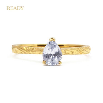 Fancy Athena ethical solitaire engagement ring in 18ct recycled yellow gold, hand-engraved and set with a ice grey pear-cut sapphire of fair-traded and traceable Sri Lankan provenance
