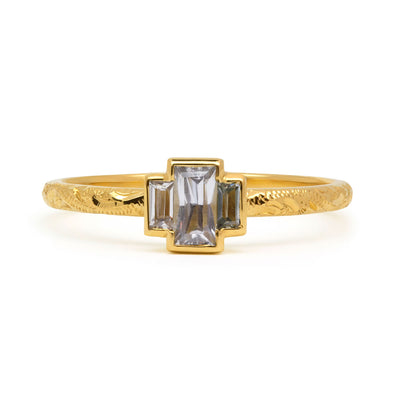Fancy Hera ethical trilogy engagement ring in 18ct recycled yellow gold, hand-engraved and set with three grey baguette sapphires of fair-traded and traceable Sri Lankan provenance