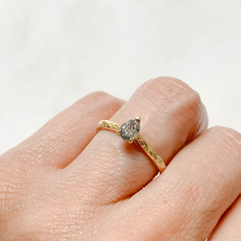 Fancy Athena ethical solitaire engagement ring in 18ct recycled yellow gold, hand-engraved and set with a pear-cut salt and pepper diamond of traceable and conflict-free Canadian provenance