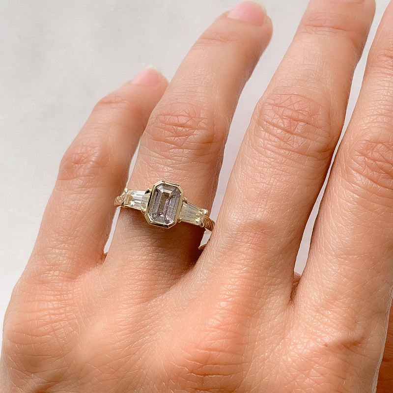 Lebrusan Studio Fancy Athena trilogy engagement ring with hand-engraved 18ct yellow Fairmined Eco Gold band and three emerald cut grey sapphires of ethical traceable origin