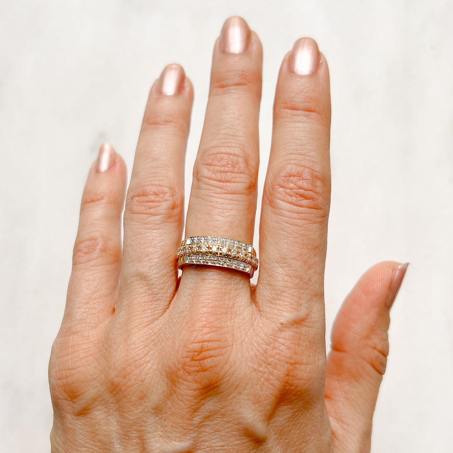Reclaimed Vintage unique commitment ring, soldering together three antique Victorian half-diamond eternity rings in 9ct yellow and rose gold, on hand