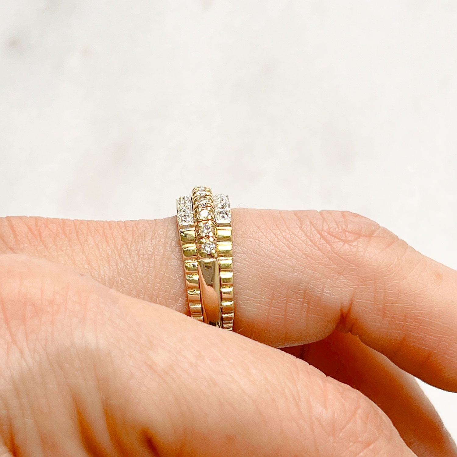 Reclaimed Vintage unique commitment ring, soldering together three antique Victorian half-diamond eternity rings in 9ct yellow and rose gold, on hand side view