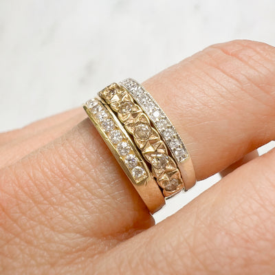 Three antique 9ct gold Victorian eternity rings half-set with diamonds, soldered together into a chunky stack, on hand, close-up view