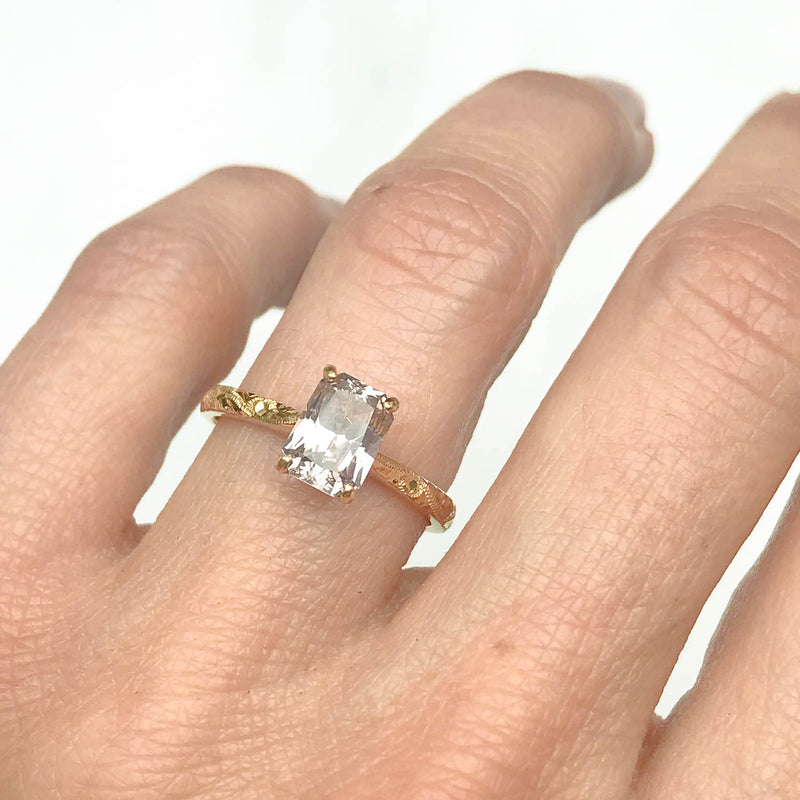 Fancy Athena ethical solitaire engagement ring in 18ct yellow Fairtrade Gold, hand-engraved and set with a pink emerald-cut sapphire of traceable and fair-traded Sri Lankan provenance