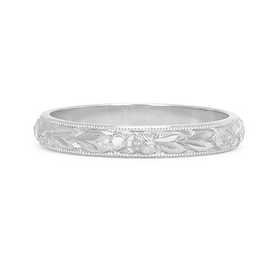 A D-shaped 2mm wedding band in 18ct recycled white gold, carefully hand-engraved with a repetitive orange blossom motif and a border of milgrain beading