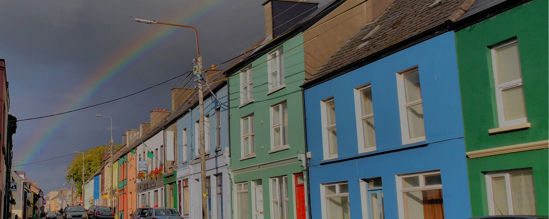 A terrace of colourful houses in Brighton & Hove, framed by a rainbow in the sky