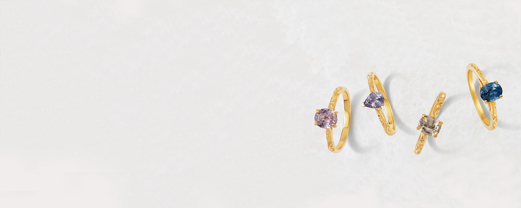 Lebrusan Studio's Fancy Athena collection of colorful engagement rings. Thin gold bands are hand-engraved with delicate scrolls and fair-traded coloured Sri Lankan sapphires are secured in raised claw settings