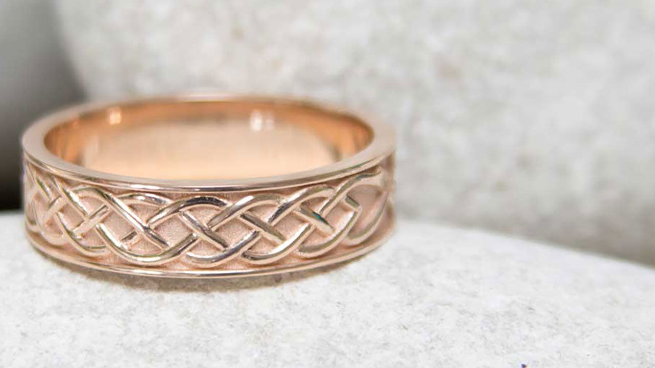 A custom rose gold mens wedding ring. A 5mm rose gold band is hand-engraved with Celtic knots. Unique custom wedding bands