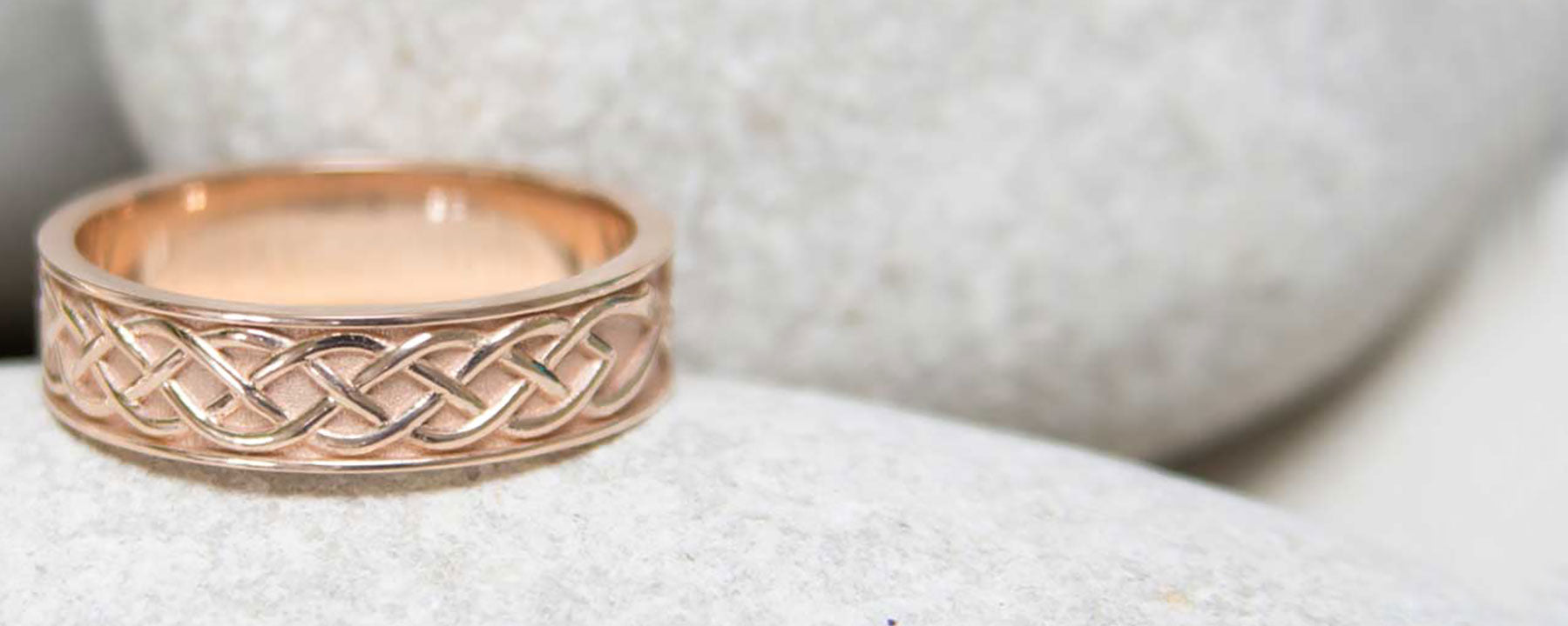 A custom rose gold mens wedding ring. A 5mm rose gold band is hand-engraved with Celtic knots. Unique custom wedding bands