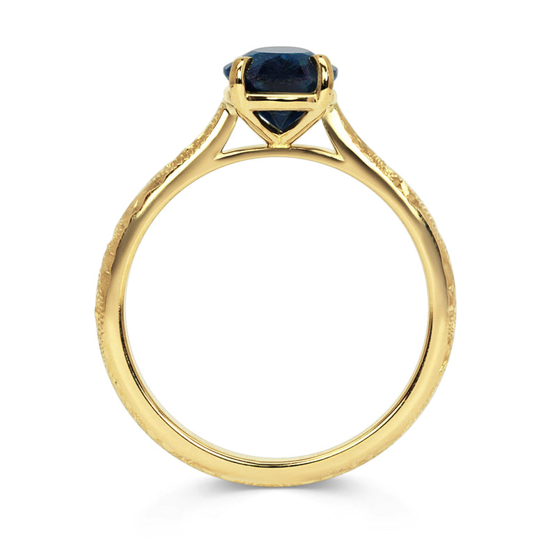 Solitaire engagement ring with a large pear-cut blue sapphire secured in a classic claw solitaire setting. 18ct recycled gold is hand engraved with scrolls