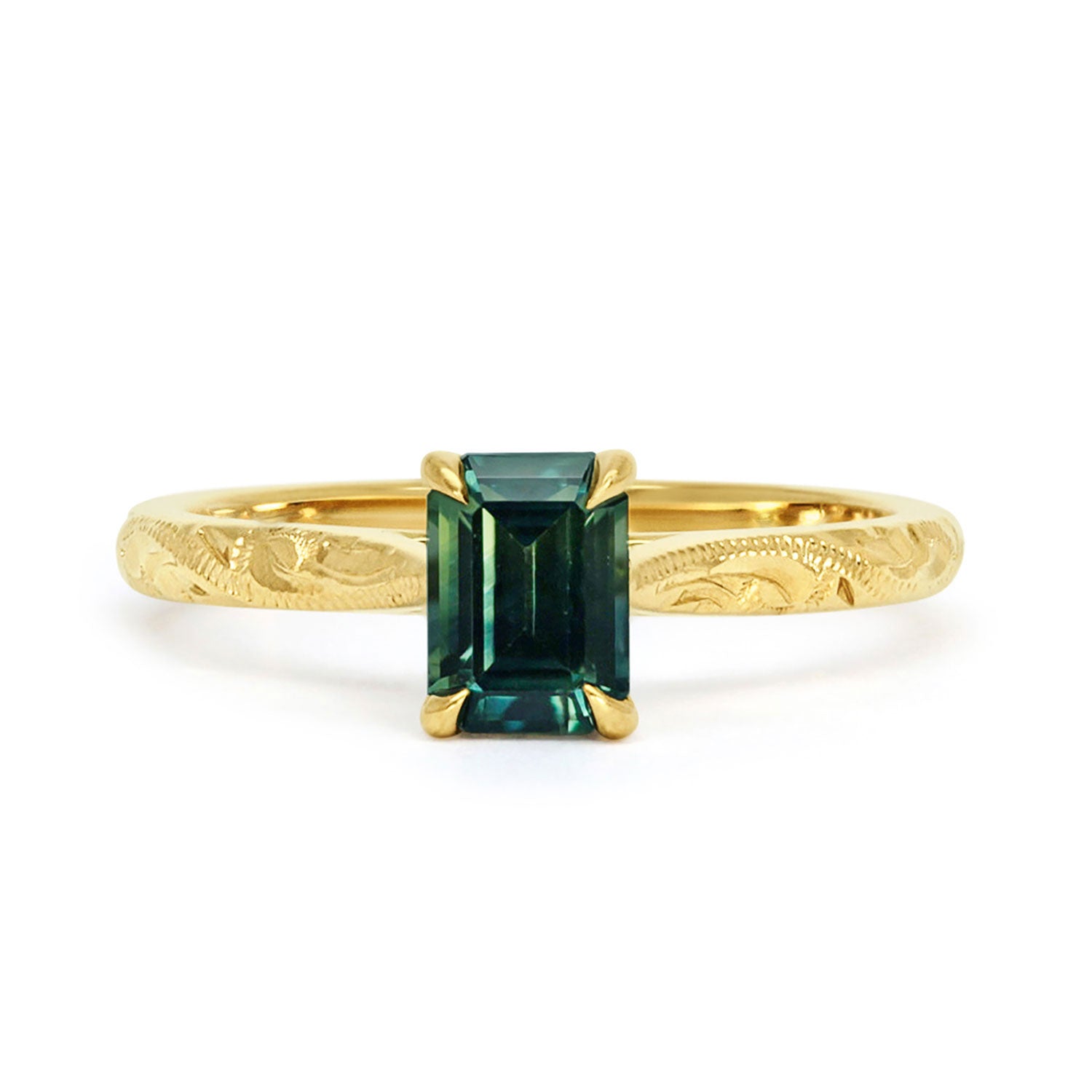 18ct recycled gold solitaire engagement ring with a baguette teal sapphire in a classic solitaire claw setting and a hand engraved band