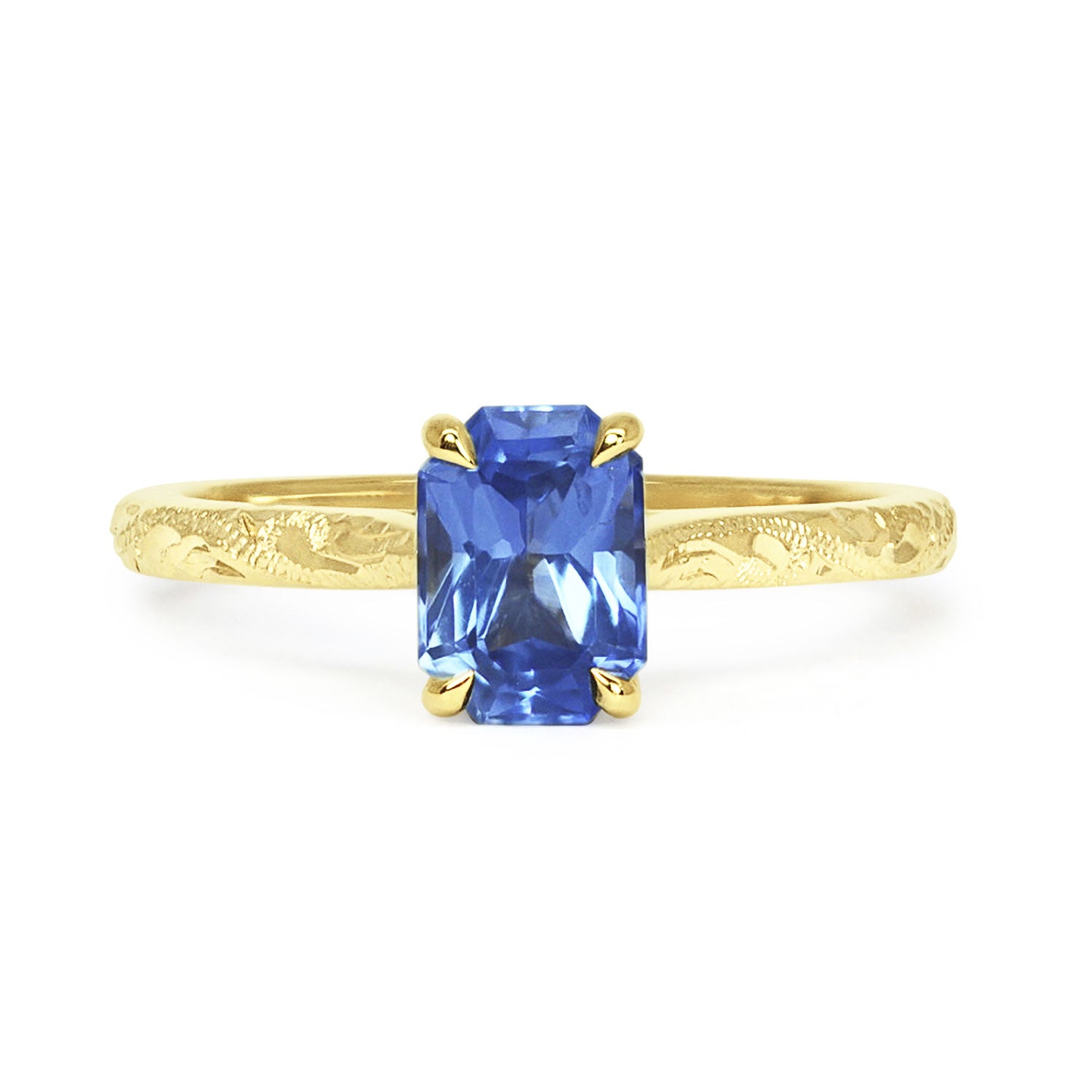 Lebrusan Studio Athena solitaire engagement ring with a hand-engraved 18ct yellow gold band and an emerald-cut blue sapphire 
