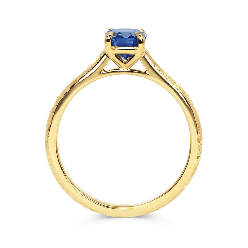 Lebrusan Studio Athena solitaire engagement ring with a hand-engraved 18ct yellow gold band and an emerald-cut blue sapphire 