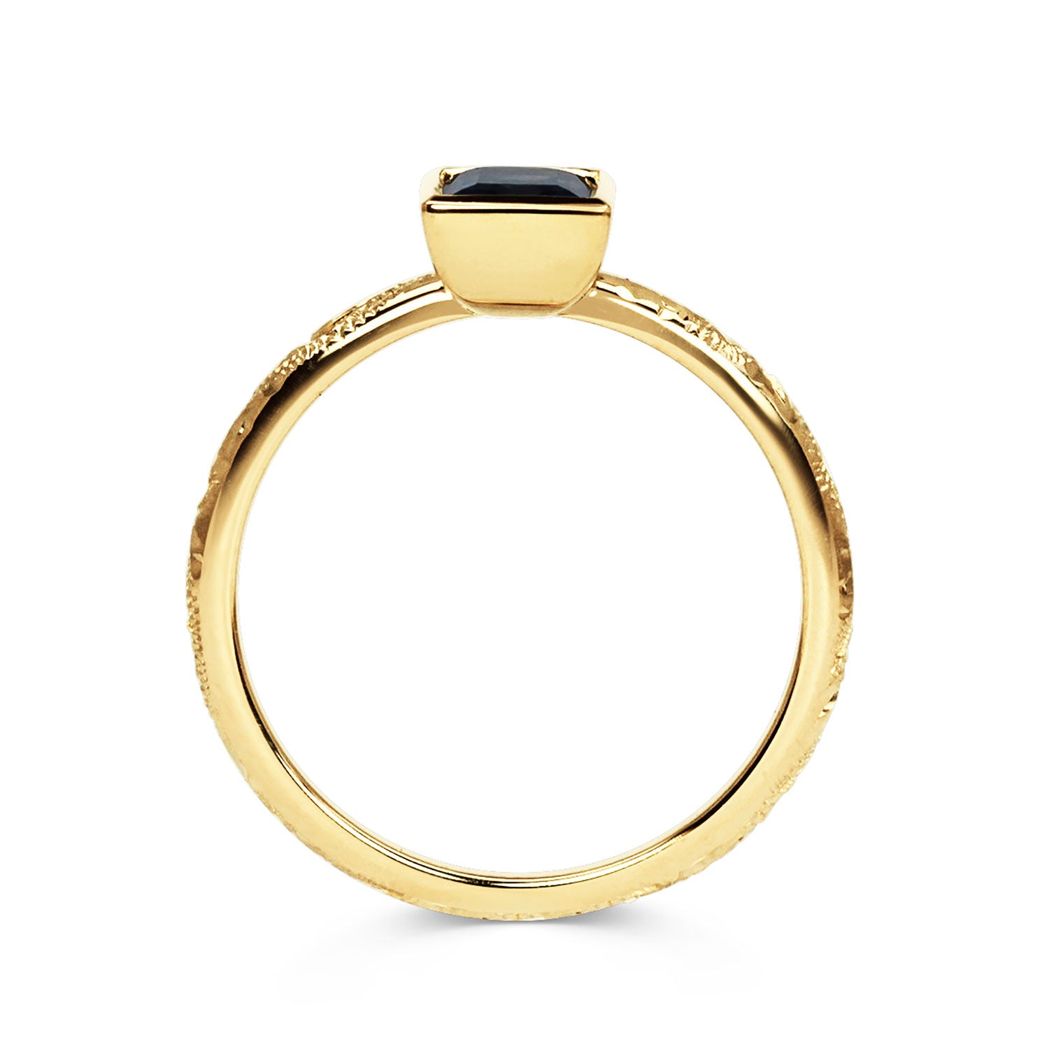 Solitaire engagement ring with a baguette-cut deep blue sapphire, secured in an 18ct recycled gold rub-over setting and a band hand-engraved with scrolls, side view
