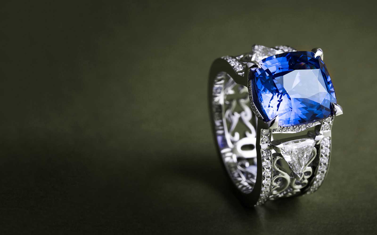 A bespoke cocktail ring, boasting a cushion-cut blue sapphire, conflict-free diamonds and intricate filigree work