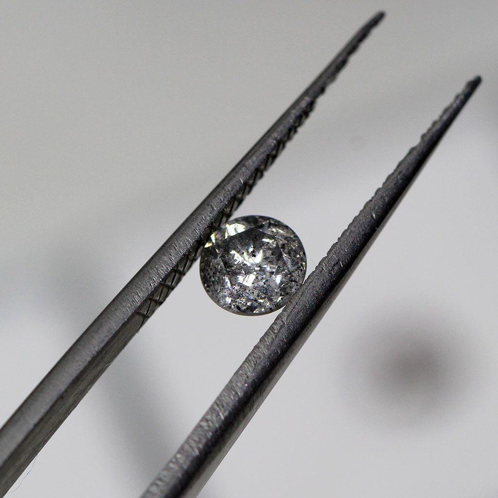 A round brilliant-cut salt and pepper diamond, ready to be set into a unique and ethical solitaire engagement ring