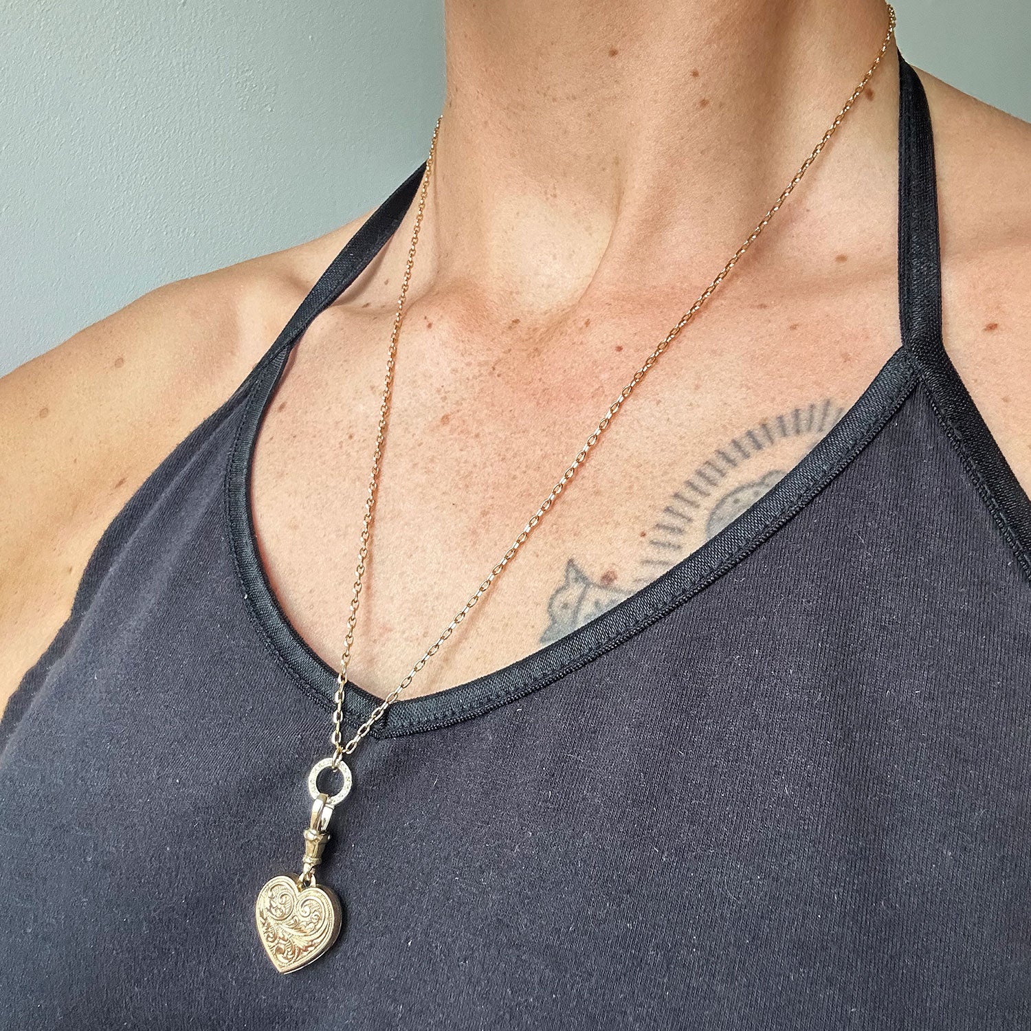 Reclaimed antique Victorian hand-engraved gold heart-shaped locket pendant necklace on a reclaimed antique gold chain, with a circlet connector in sustainable recycled gold and conflict-free Canadian diamonds, modelled on body 2