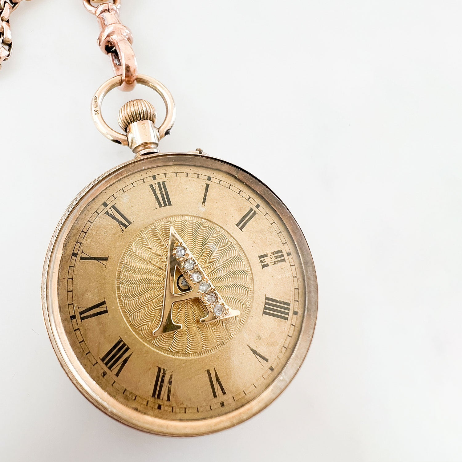 Reclaimed Vintage antique Victotrian pocket watch with Roman numerals and a decorative 'A', set with broken diamonds - repurposed as a pendant on a reclaimed antique gold chain and Albert clasp - on a white background