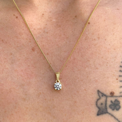 Lebrusan Studio's ethical Perfectus pendant necklace, crafted in London, UK, using 18ct Fairtrade Gold and a recycled diamond. A hand-engraved floral motif and proud claw setting are finishing touches. Close-up shot on a model's chest