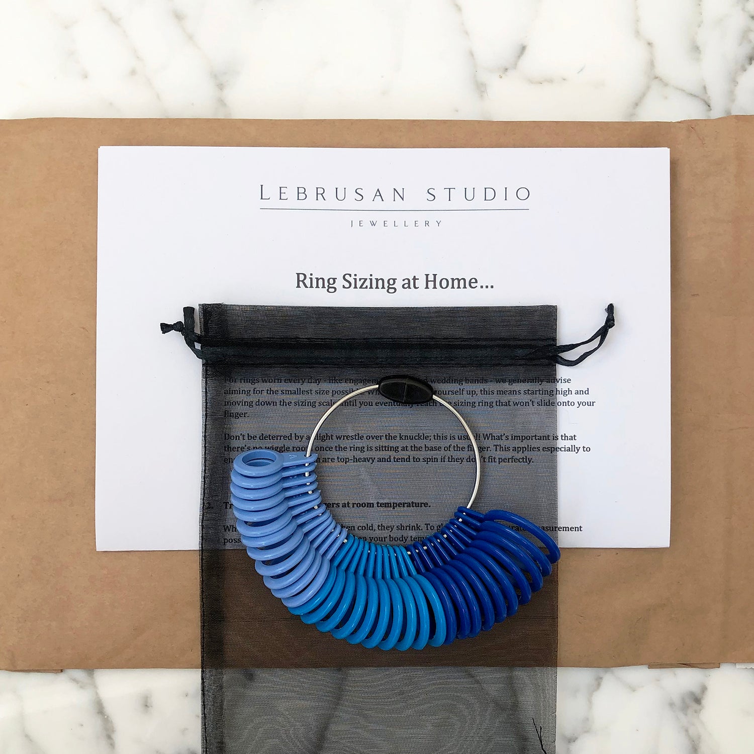 A Lebrusan Studio ring sizer loan for ensuring the perfect engagement ring or wedding band fit. A home ring sizing gauge is packaged up in an eco-friendly envelope with helpful jewellery sizing tips. 