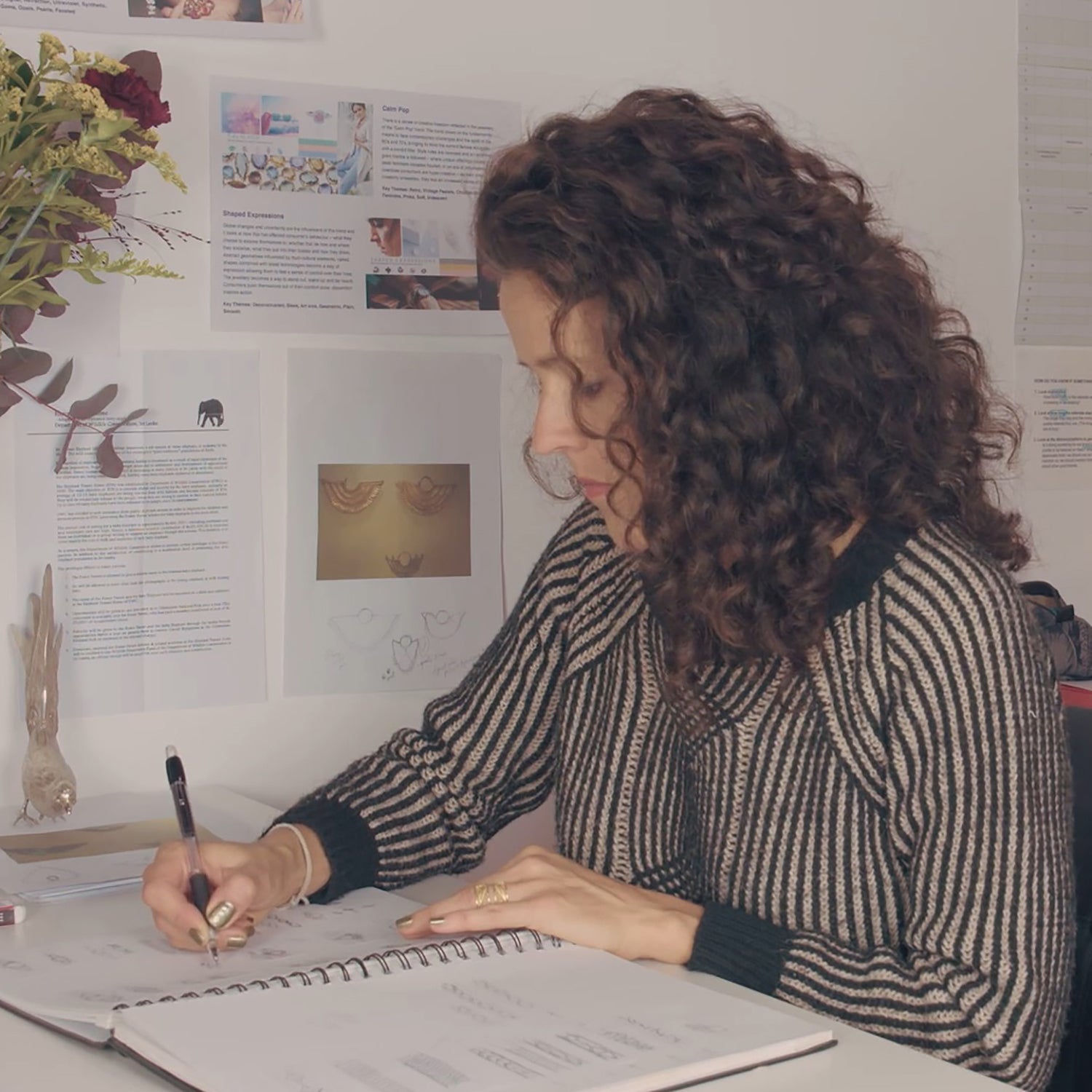 Arabel Lebrusan, leading figure in ethical London designer jewellery, sitting in her Brighton jewellery studio drawing up bespoke jewellery designs in her notebook. 