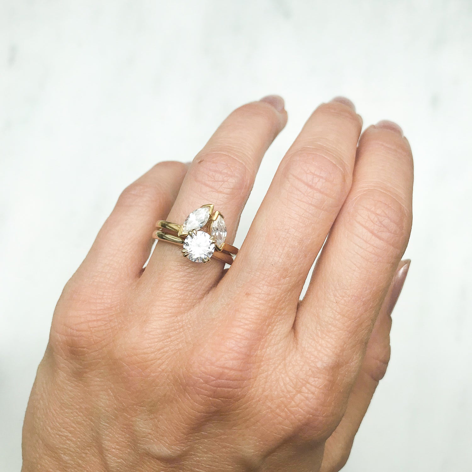 Lebrusan Studio Artisan Ethical Diamond Solitaire Engagement Ring, 1ct Ocean Diamond, 18ct Fairmined Ecological Gold, on the hand alongside the shaped Marquise Diadem Ethical Diamond Wedding Ring