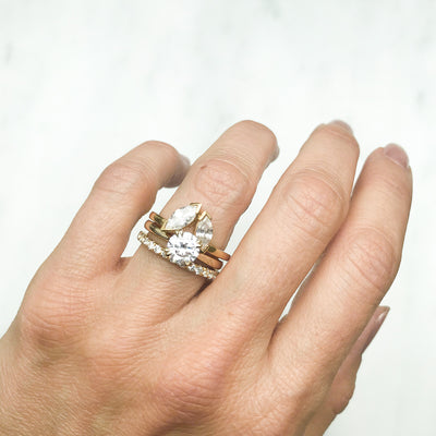 Lebrusan Studio Artisan Ethical Diamond Solitaire Engagement Ring, 1ct Ocean Diamond, 18ct Fairmined Ecological Gold, on the hand alongside the shaped Marquise Diadem Ethical Diamond Wedding Ring and the Altair Microset Ethical Diamond Eternity Ring